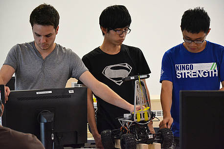 Teilnehmer der Robot Operating-Summerschool arbeiten an einem Versuch mit einem fahrbaren Roboter