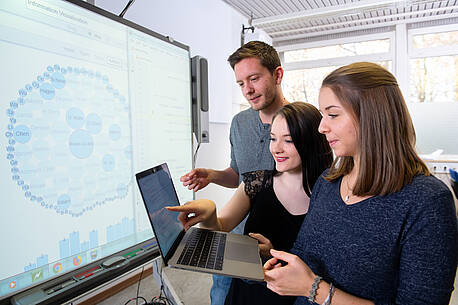 Symbolbild für neuen Studiengang Information Science an der Hochschule Darmstadt: 3 Studierende vor einem Laptop.